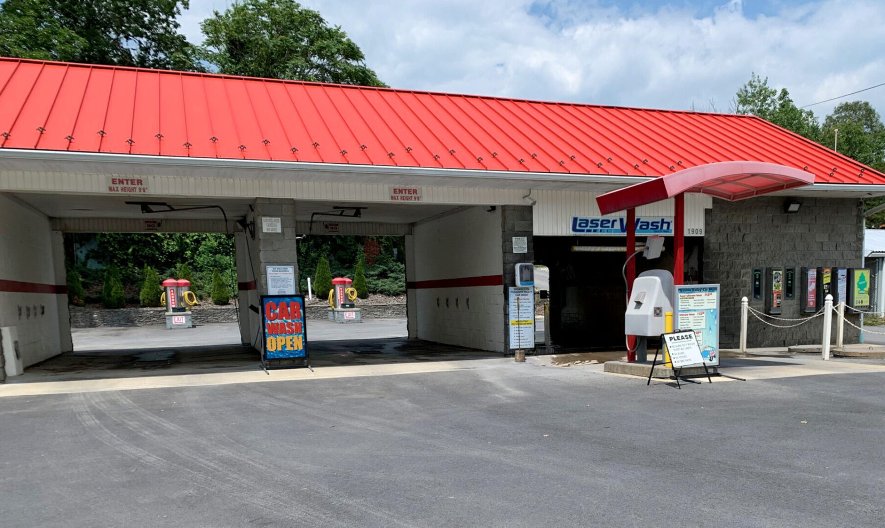A red-roofed car wash with two bays under a blue sky.